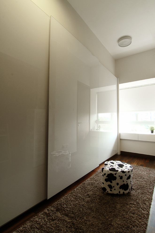 Modernes Ankleidezimmer mit Ankleidebereich, Glasfronten, weißen Schränken und dunklem Holzboden in Singapur