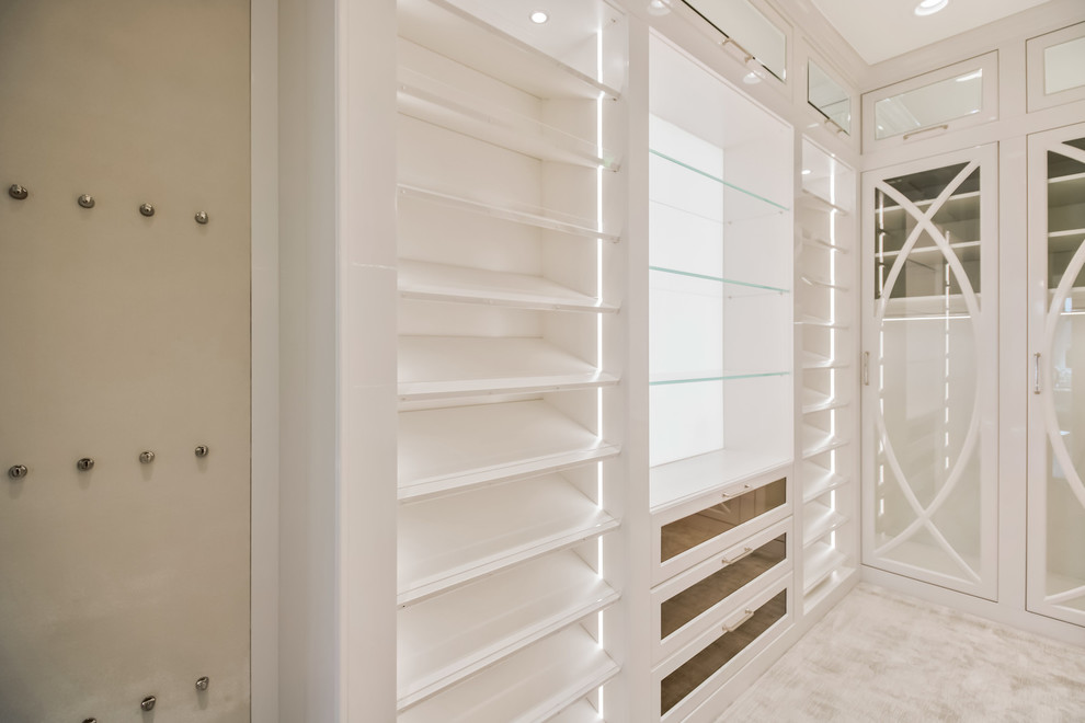 マイアミにあるラグジュアリーな広いトランジショナルスタイルのおしゃれなウォークインクローゼット (フラットパネル扉のキャビネット、白いキャビネット、カーペット敷き) の写真