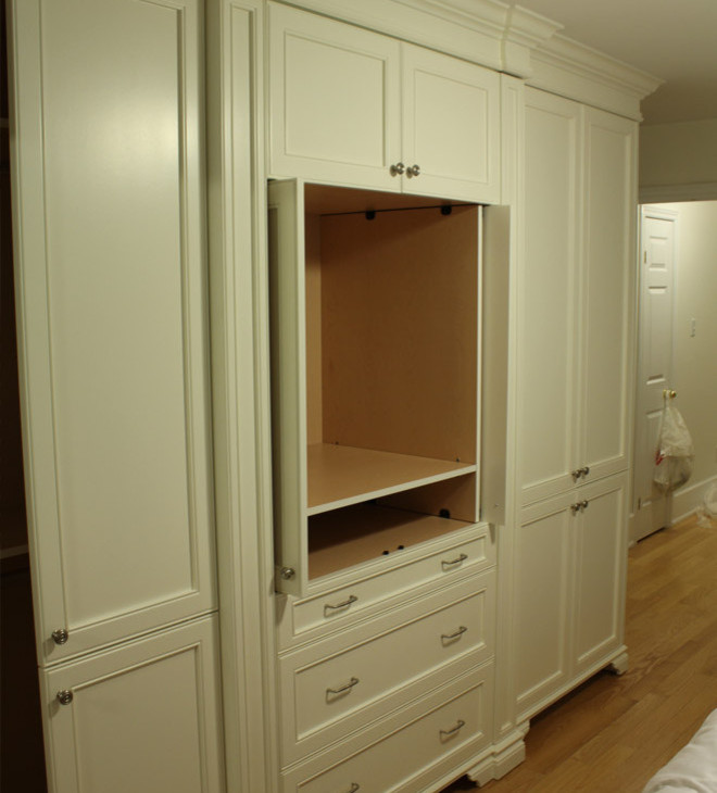 Ejemplo de armario unisex tradicional pequeño con armarios con paneles empotrados, puertas de armario blancas y suelo de madera en tonos medios