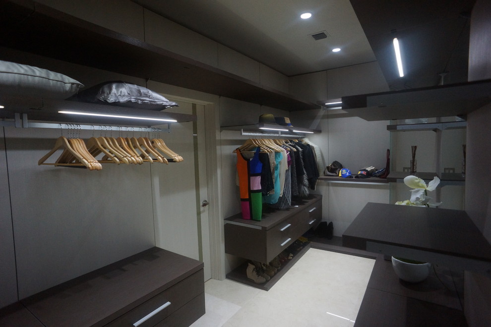 Ejemplo de armario vestidor unisex moderno grande con armarios con paneles lisos, puertas de armario de madera en tonos medios y suelo de baldosas de porcelana