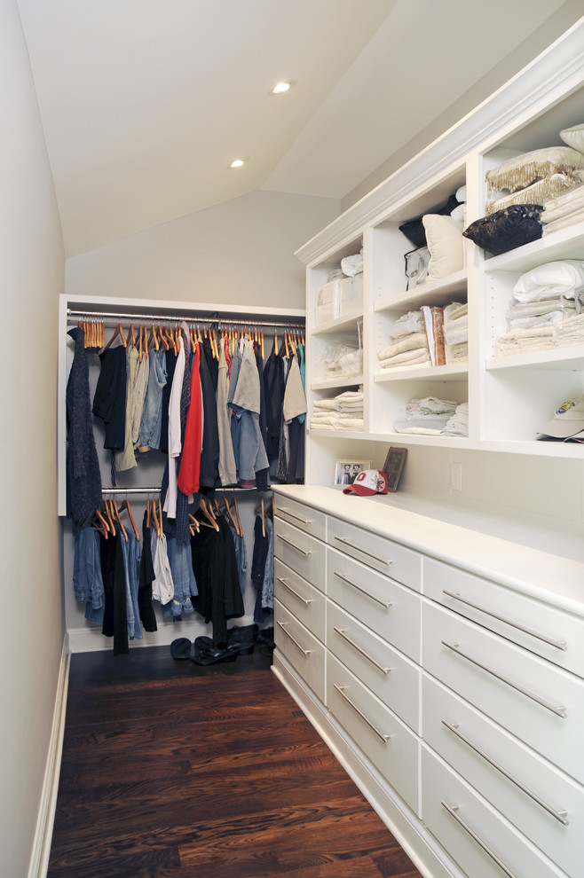 Ejemplo de vestidor unisex actual de tamaño medio con armarios con paneles lisos, puertas de armario blancas y suelo de madera en tonos medios