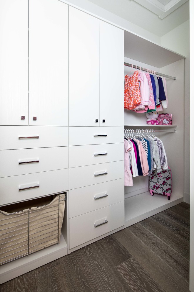 Ejemplo de armario vestidor de mujer actual pequeño con armarios con paneles lisos, puertas de armario blancas, suelo de madera en tonos medios y suelo marrón