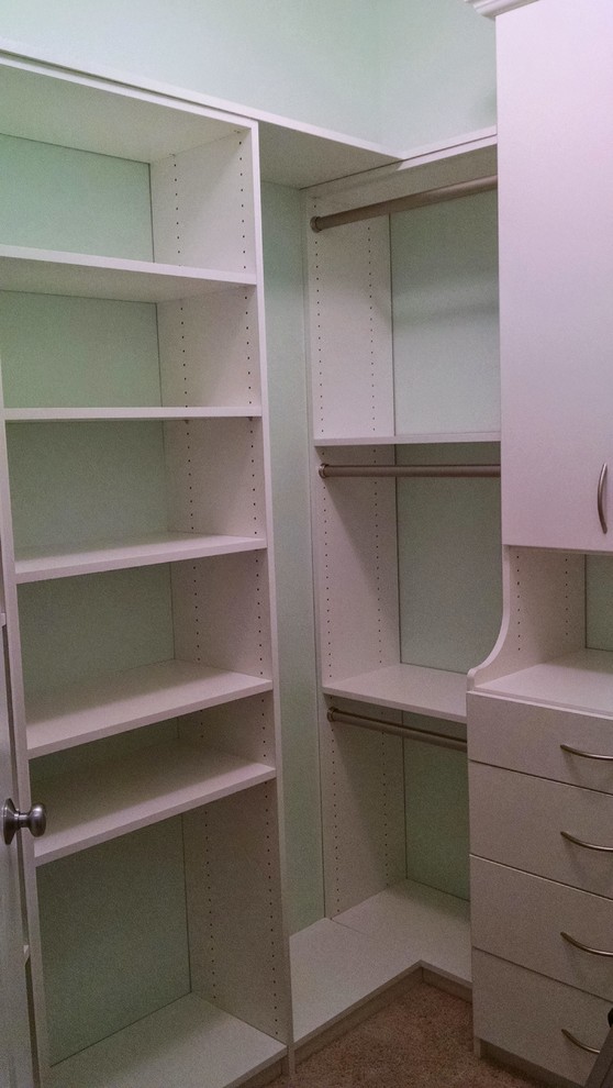 Ejemplo de armario vestidor unisex tradicional de tamaño medio con armarios con paneles lisos, puertas de armario blancas y suelo de madera oscura