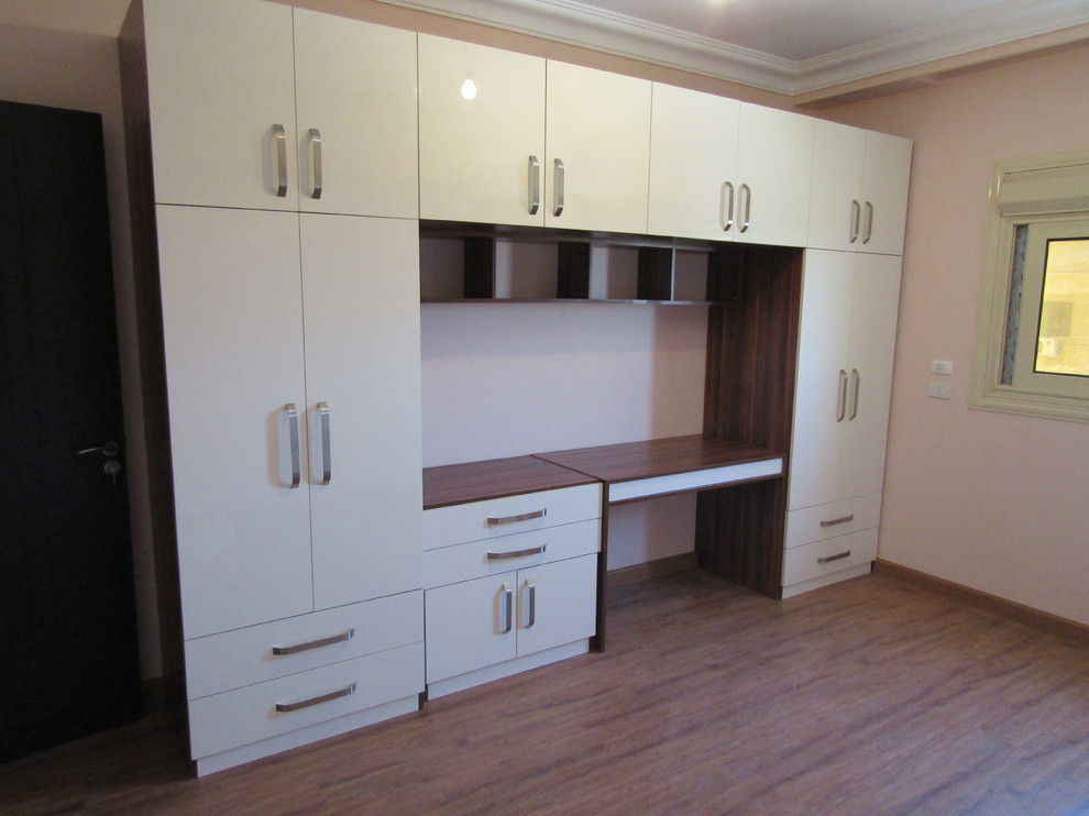 Ejemplo de armario unisex minimalista grande con armarios con paneles lisos, puertas de armario beige, suelo laminado y suelo marrón