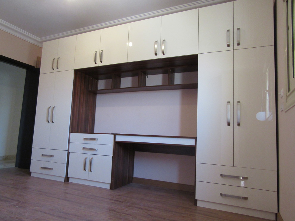 Diseño de armario unisex moderno grande con armarios con paneles lisos, puertas de armario beige, suelo laminado y suelo marrón