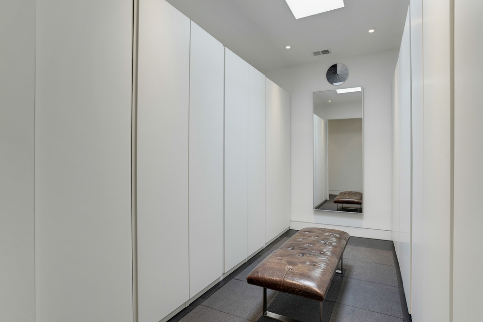 Imagen de armario vestidor unisex minimalista con armarios con paneles lisos, puertas de armario blancas, suelo de baldosas de cerámica y suelo marrón