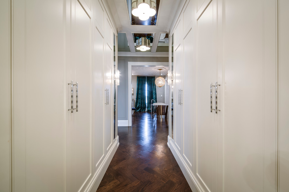 Cette photo montre un dressing room moderne de taille moyenne et neutre avec un placard à porte affleurante, des portes de placard blanches et un sol en bois brun.