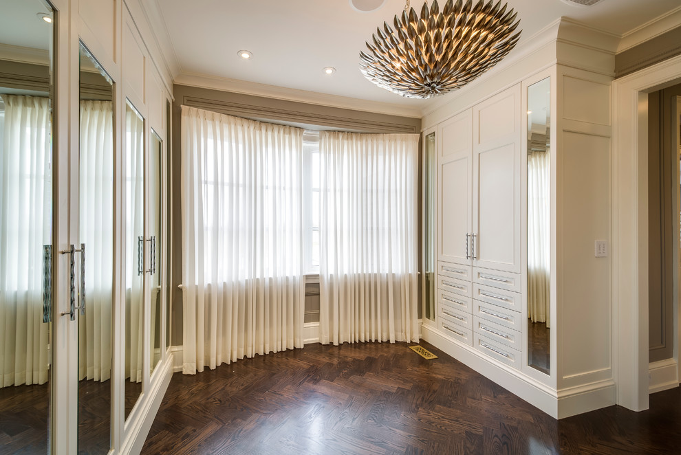 Medium sized modern gender neutral dressing room in Toronto with white cabinets, medium hardwood flooring and recessed-panel cabinets.
