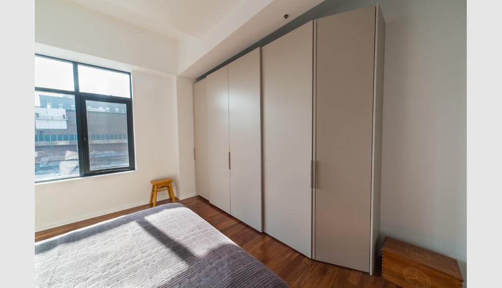 Diseño de armario unisex actual grande con armarios con paneles lisos, puertas de armario beige y suelo de madera en tonos medios