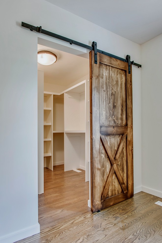 Diseño de armario vestidor unisex campestre de tamaño medio con suelo de madera en tonos medios y suelo marrón