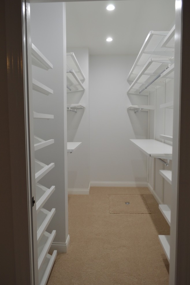 Medium sized traditional gender neutral walk-in wardrobe in Detroit with carpet and beige floors.