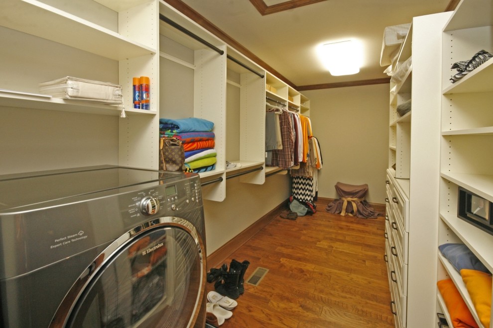 This is an example of a large classic gender neutral walk-in wardrobe in Other with white cabinets and medium hardwood flooring.