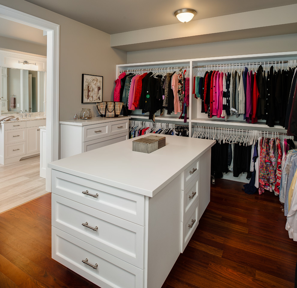 Large traditional gender neutral walk-in wardrobe in Other with recessed-panel cabinets, white cabinets and medium hardwood flooring.