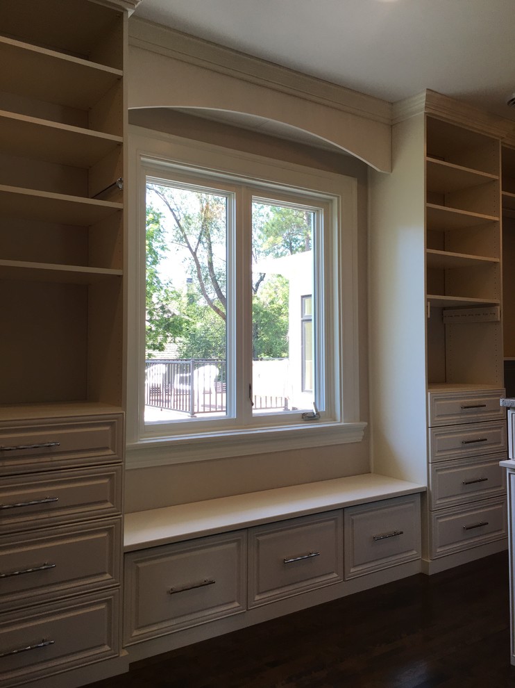Medium sized traditional gender neutral walk-in wardrobe in Minneapolis with raised-panel cabinets, white cabinets and dark hardwood flooring.