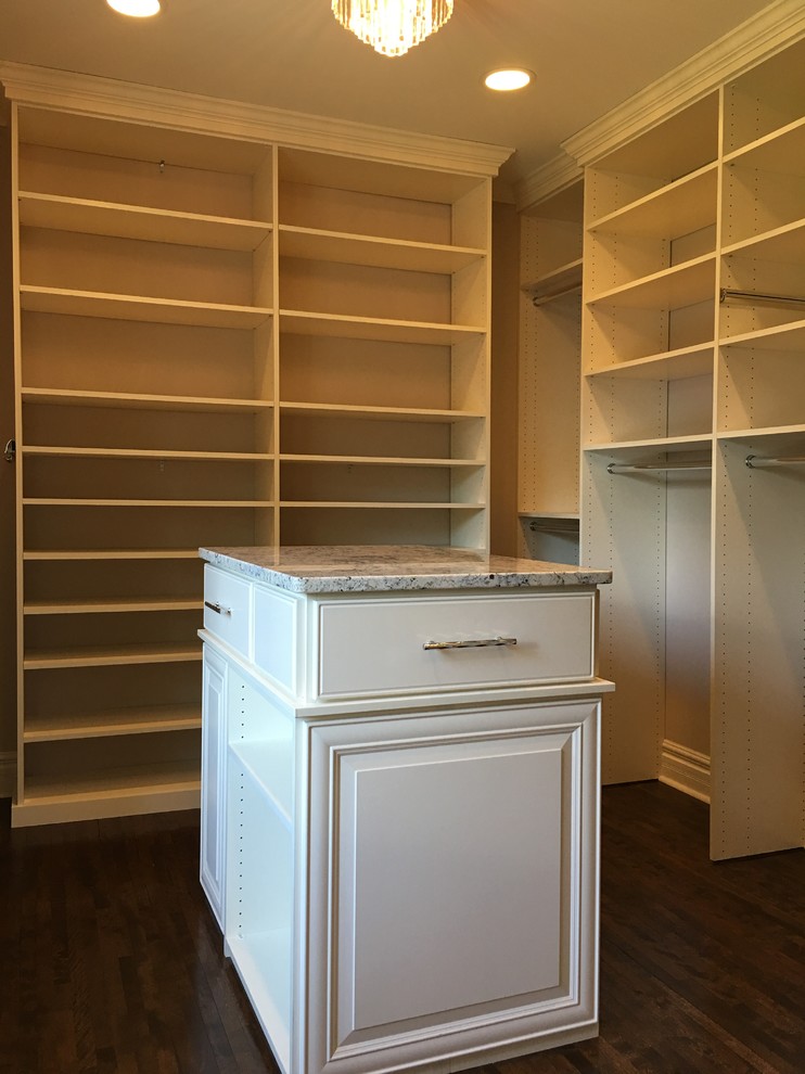 Foto de armario vestidor unisex clásico de tamaño medio con armarios con paneles con relieve, puertas de armario blancas y suelo de madera oscura