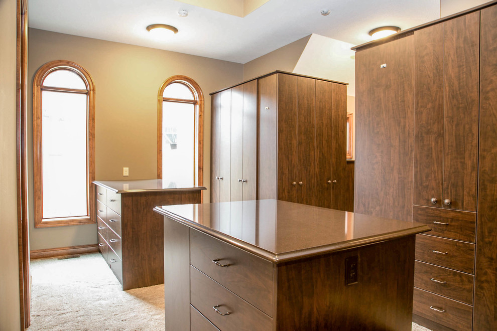 На фото: гардеробная комната унисекс в классическом стиле с плоскими фасадами, фасадами цвета дерева среднего тона и ковровым покрытием с