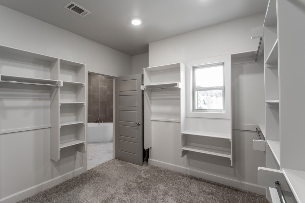 Imagen de armario vestidor unisex clásico de tamaño medio con armarios abiertos, puertas de armario blancas, moqueta y suelo marrón