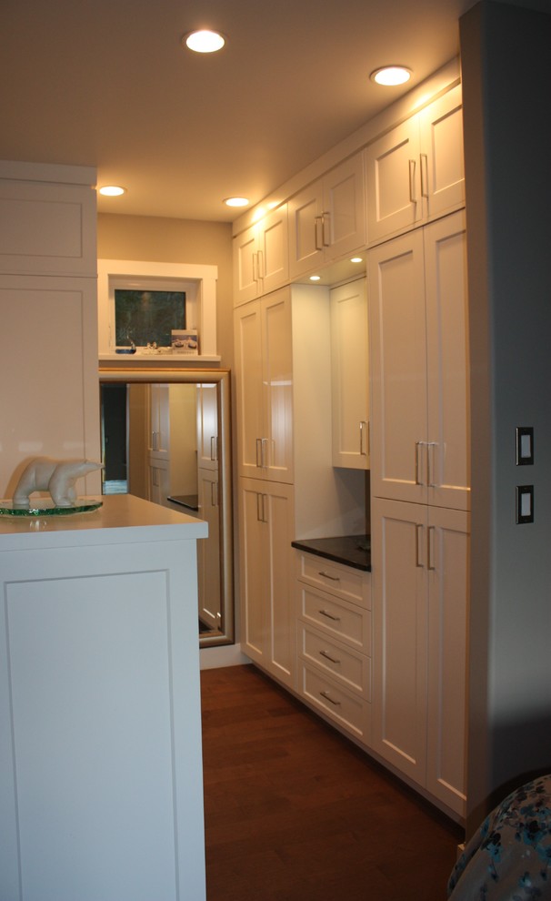 This is an example of a small contemporary gender neutral walk-in wardrobe in Vancouver with shaker cabinets, white cabinets and dark hardwood flooring.