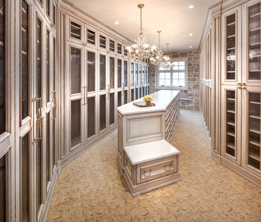Идея дизайна: большая гардеробная комната унисекс в викторианском стиле с стеклянными фасадами, светлыми деревянными фасадами, ковровым покрытием и бежевым полом