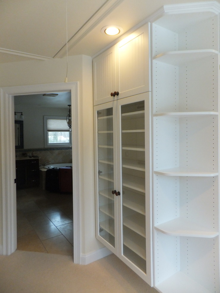 Example of a mid-sized beach style gender-neutral carpeted dressing room design in Manchester with glass-front cabinets and white cabinets