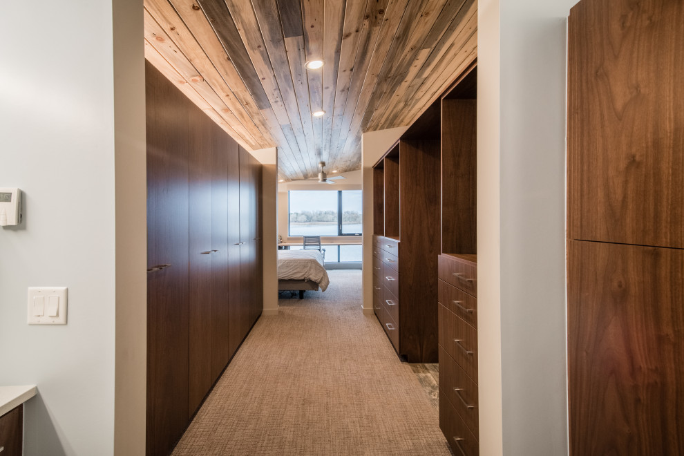 Cette image montre un grand dressing room chalet en bois foncé neutre avec un placard à porte plane, moquette et un sol beige.