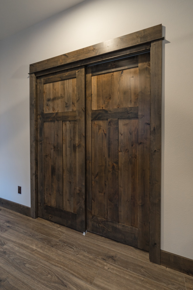 This is an example of a medium sized rustic gender neutral standard wardrobe in Other with laminate floors and brown floors.
