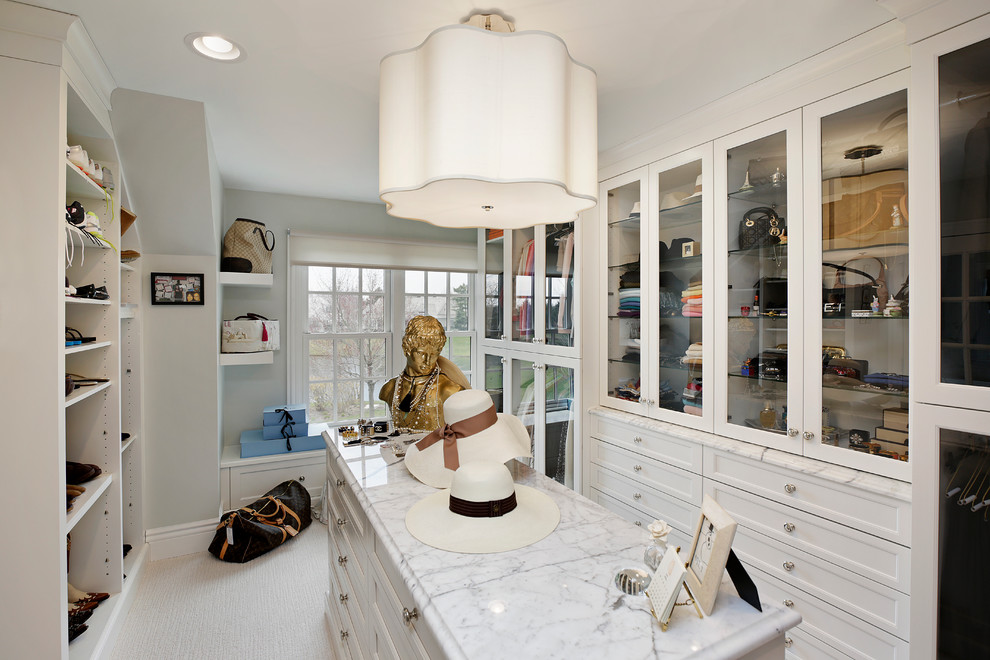 На фото: большая гардеробная комната унисекс в классическом стиле с стеклянными фасадами, белыми фасадами и ковровым покрытием с