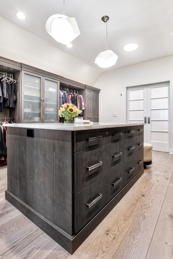 Modelo de armario vestidor unisex clásico renovado extra grande con armarios con paneles lisos, puertas de armario de madera en tonos medios y suelo de madera clara