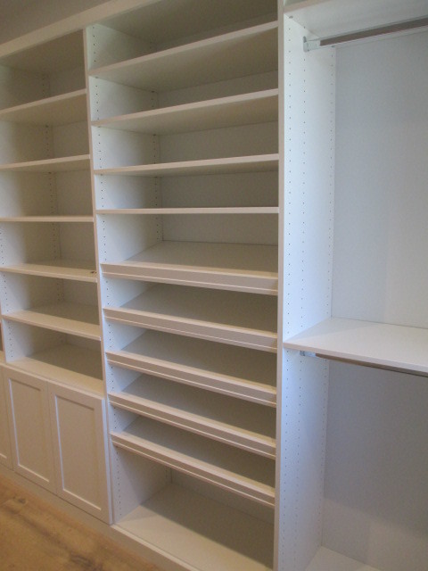 Imagen de armario vestidor unisex costero grande con armarios estilo shaker, puertas de armario blancas y suelo de madera clara
