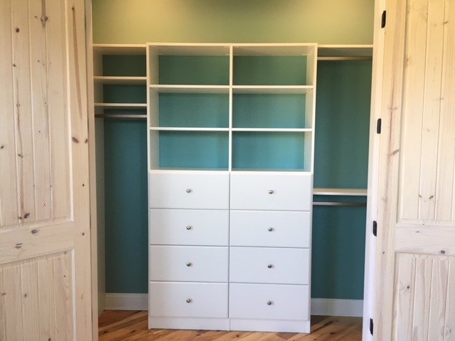 This is an example of a large classic gender neutral standard wardrobe in Other with flat-panel cabinets, white cabinets, medium hardwood flooring and brown floors.