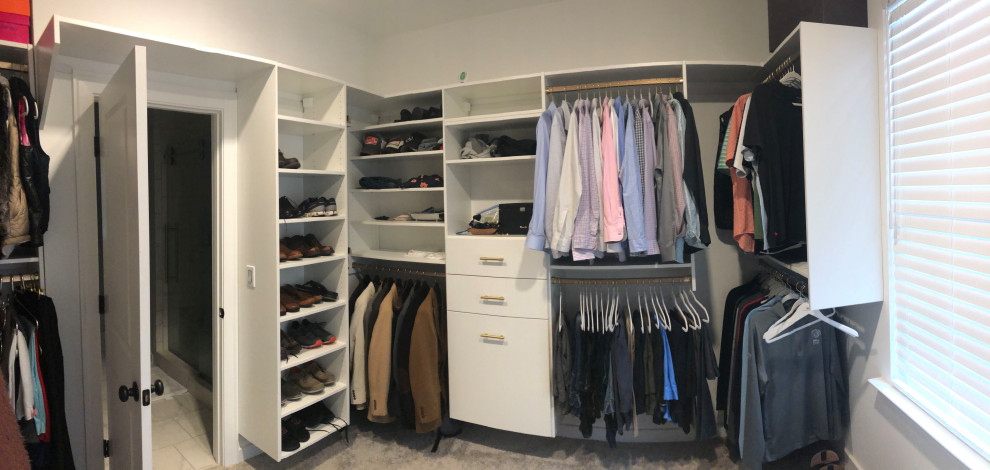 Design ideas for a large modern gender neutral walk-in wardrobe in Birmingham with flat-panel cabinets, white cabinets, carpet and beige floors.