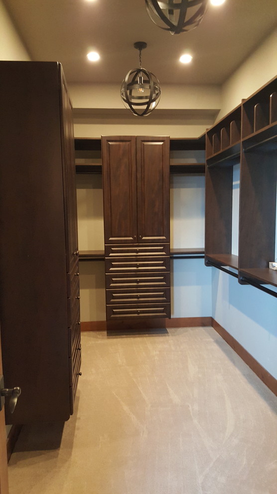 Huge elegant gender-neutral carpeted and beige floor walk-in closet photo in Seattle with raised-panel cabinets and dark wood cabinets