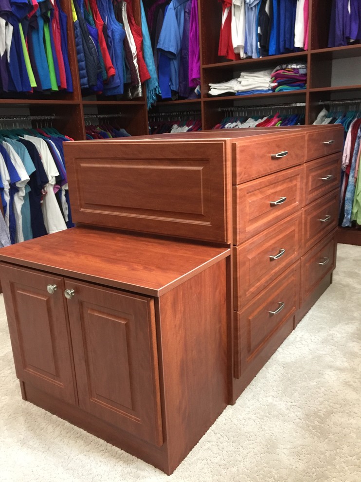 Large traditional gender neutral wardrobe in Other with raised-panel cabinets, dark wood cabinets, carpet and beige floors.