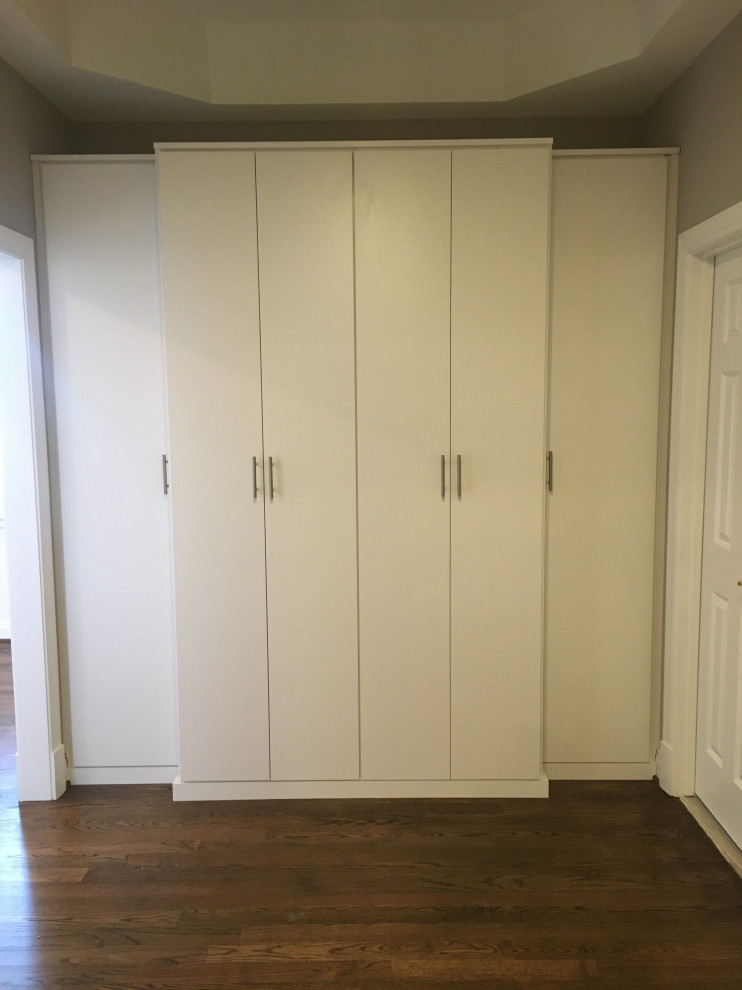 Diseño de armario y vestidor minimalista grande con a medida, puertas de armario blancas y suelo de madera oscura