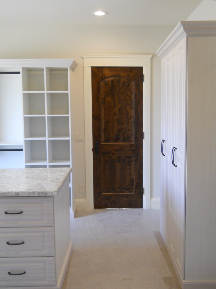 Photo of a large classic gender neutral walk-in wardrobe in Cleveland with raised-panel cabinets, white cabinets, carpet and white floors.