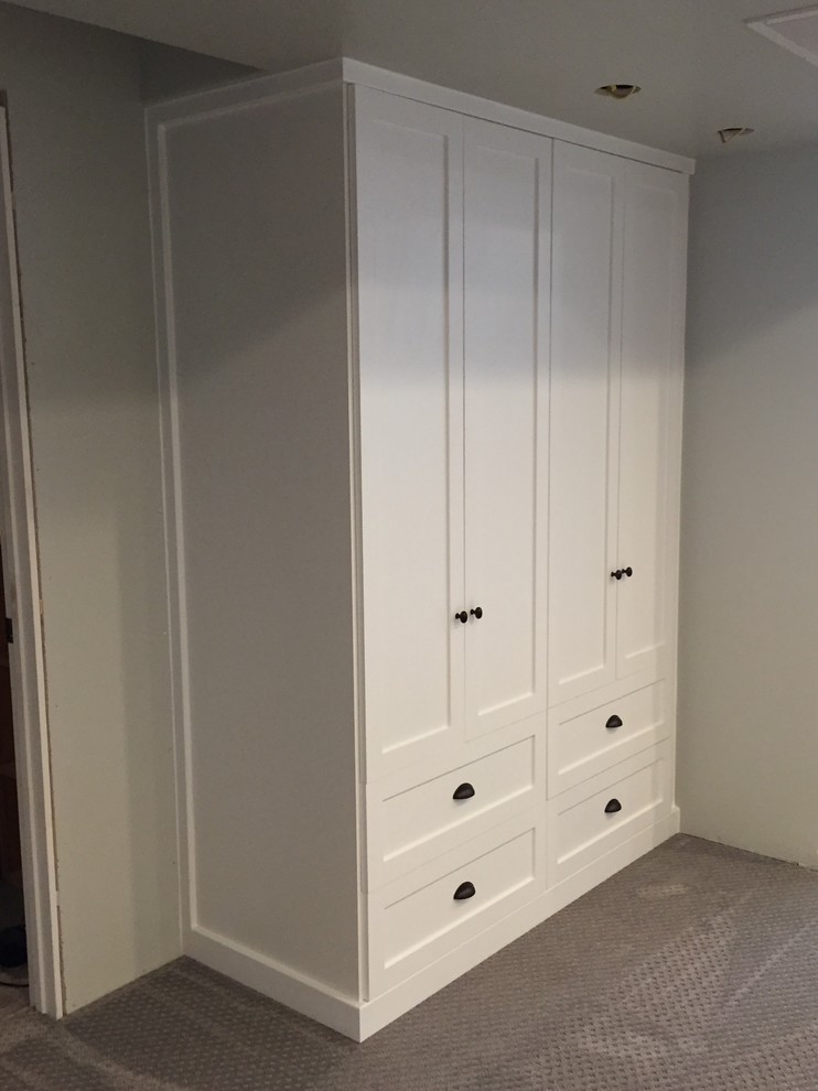Ejemplo de vestidor unisex campestre grande con armarios estilo shaker, puertas de armario blancas, moqueta y suelo marrón