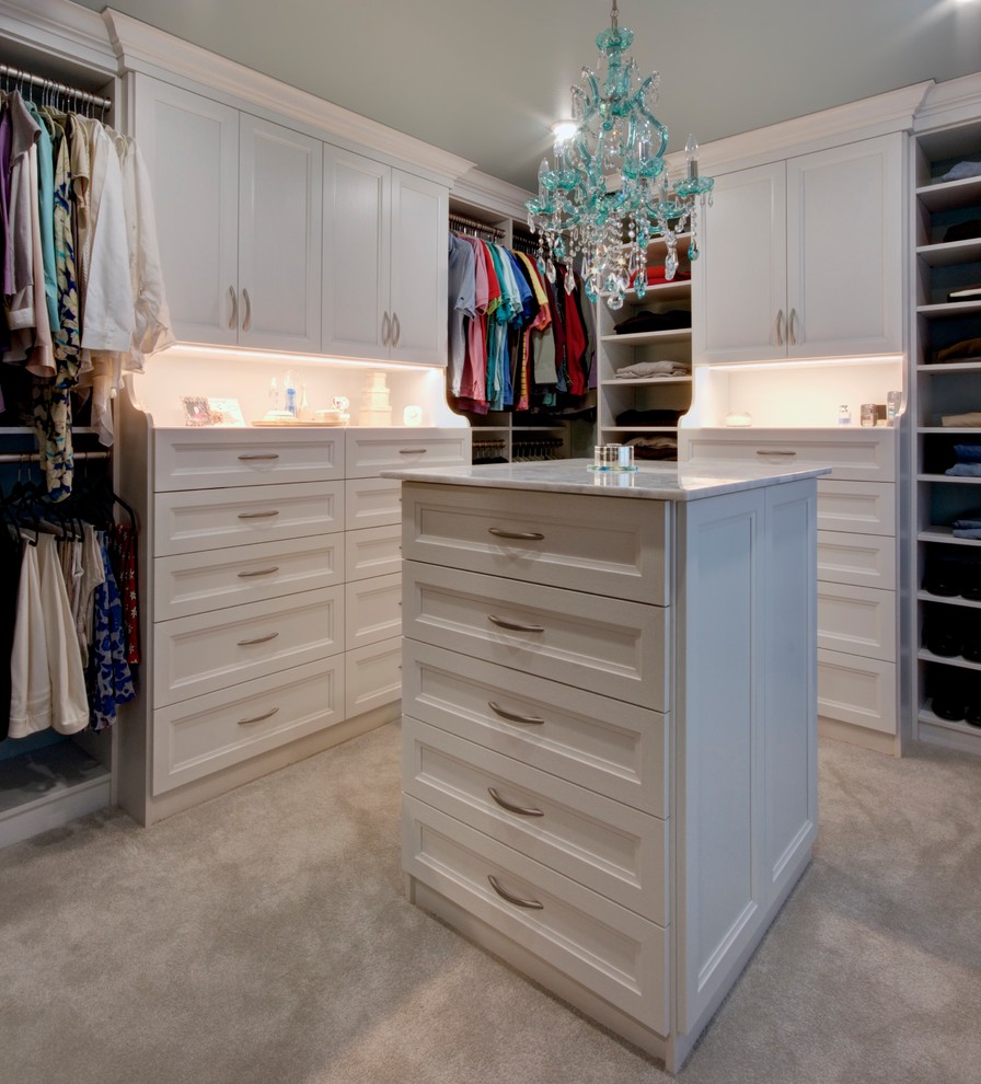 Example of a large classic gender-neutral carpeted and beige floor walk-in closet design in Other with white cabinets and recessed-panel cabinets