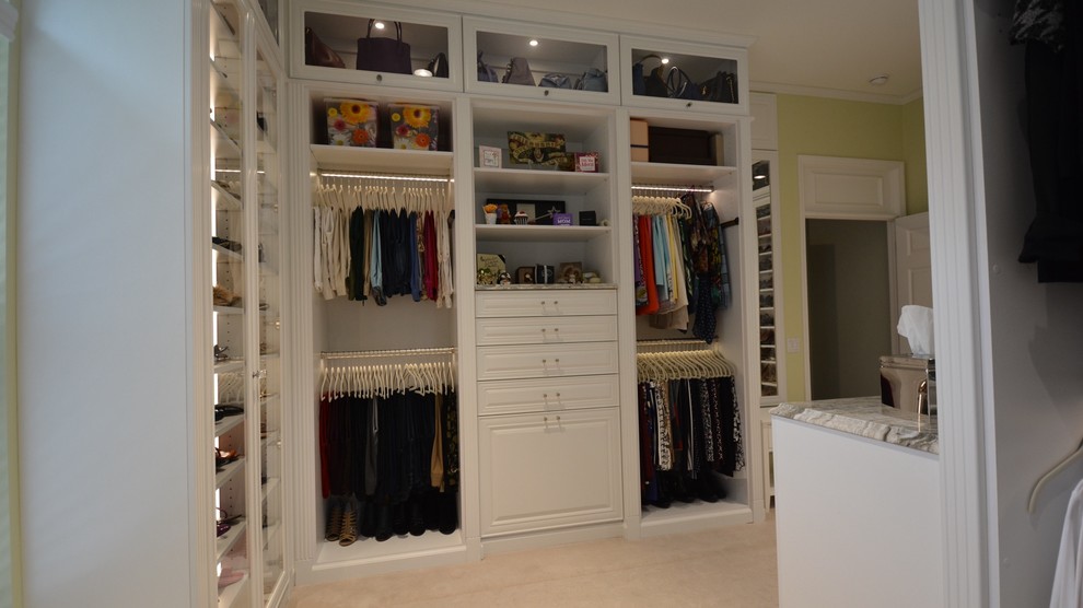 Design ideas for a large traditional walk-in wardrobe for women in Orange County with glass-front cabinets, white cabinets and carpet.