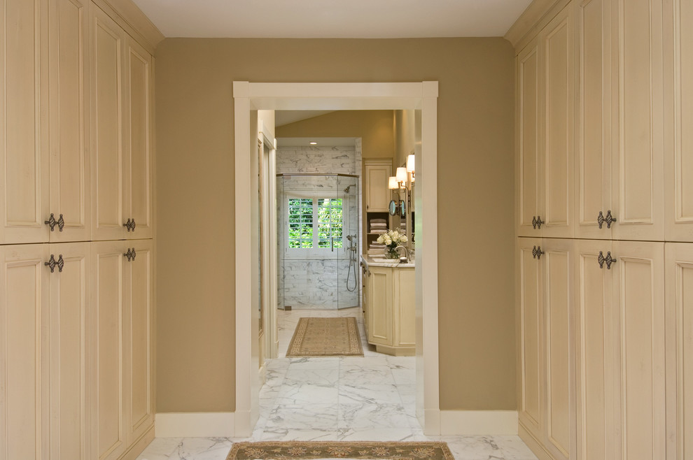 This is an example of a world-inspired walk-in wardrobe in New York with beige cabinets.