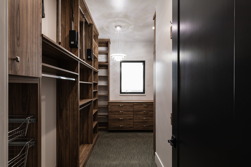 This is an example of a medium sized contemporary walk-in wardrobe for women in Salt Lake City with flat-panel cabinets, medium wood cabinets, carpet and grey floors.