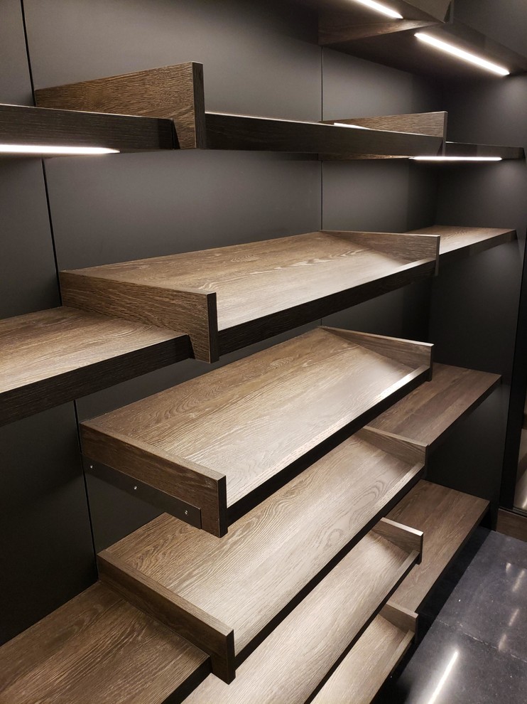 Inspiration for a large contemporary gender neutral walk-in wardrobe in Los Angeles with flat-panel cabinets, medium wood cabinets, concrete flooring and black floors.