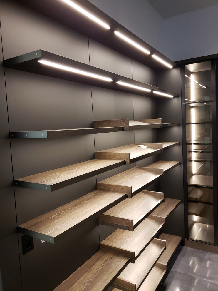 Walk-in closet - large contemporary gender-neutral concrete floor and black floor walk-in closet idea in Los Angeles with flat-panel cabinets and medium tone wood cabinets
