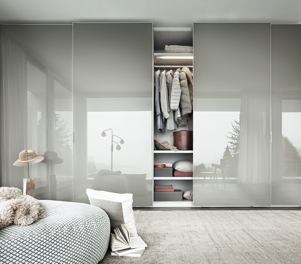 Ispirazione per un armadio o armadio a muro unisex minimalista di medie dimensioni con ante di vetro, ante bianche, parquet scuro e pavimento marrone