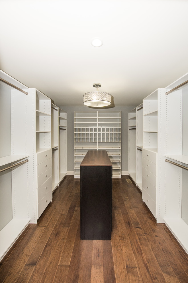 Foto di una grande cabina armadio unisex minimalista con ante bianche, parquet scuro e pavimento marrone