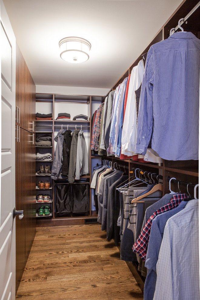 Idée de décoration pour un dressing tradition en bois foncé de taille moyenne pour un homme avec un placard à porte plane et un sol en bois brun.