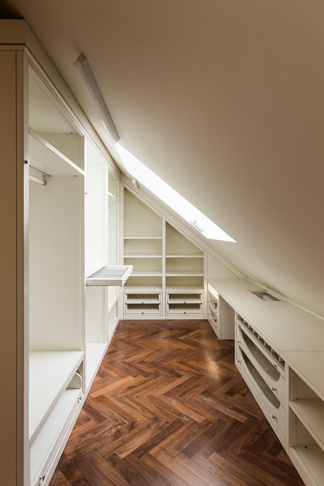 Inspiration for a contemporary gender neutral walk-in wardrobe in Moscow with white cabinets, dark hardwood flooring and brown floors.