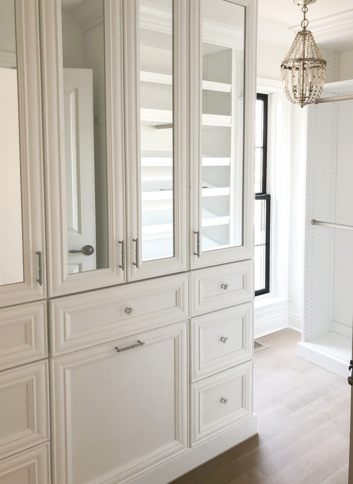 Cette image montre un petit dressing room style shabby chic pour une femme avec un placard avec porte à panneau encastré, des portes de placard blanches, parquet clair et un sol beige.