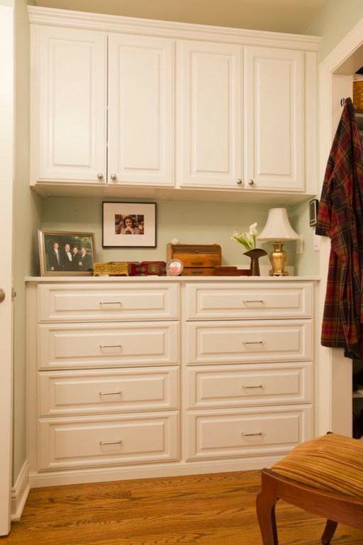 Imagen de vestidor unisex clásico de tamaño medio con armarios con paneles con relieve, puertas de armario blancas y suelo de madera en tonos medios