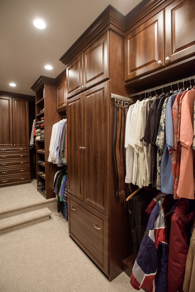 Modelo de armario y vestidor unisex tradicional con armarios abiertos, puertas de armario de madera en tonos medios, moqueta y suelo beige