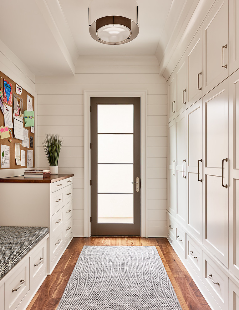 Transitional gender-neutral medium tone wood floor walk-in closet photo in Charlotte with shaker cabinets and white cabinets